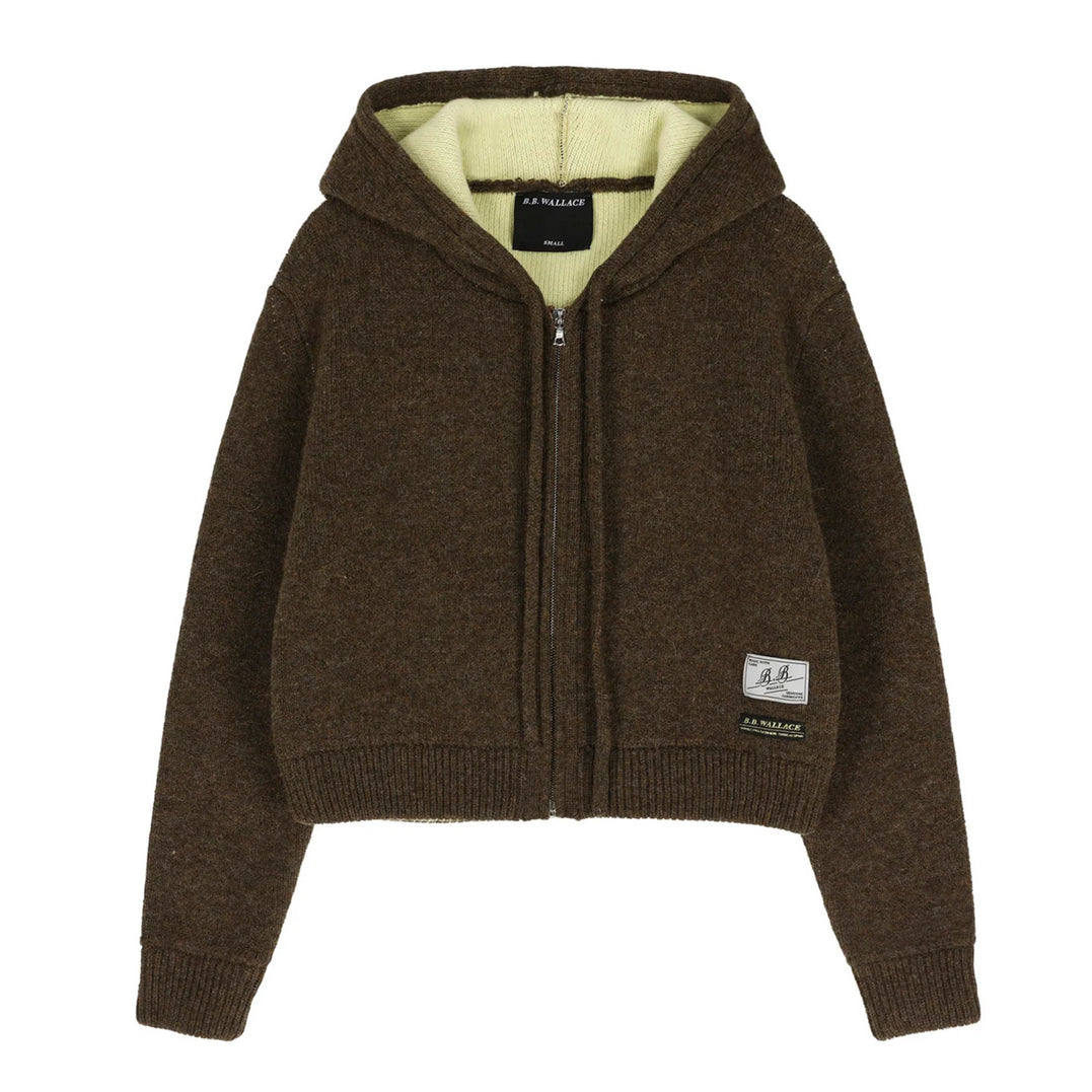 A dark brown cropped zip-up hoodie with a light yellow-green fleece lining, featuring a front zipper, ribbed cuffs and hem, and a small brand patch on the lower left sleeve.