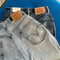 Pair of reworked vintage Levi's jeans with tags on a blue daybed