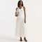 Woman wearing a white sleeveless top and pleated white skirt on a white background
